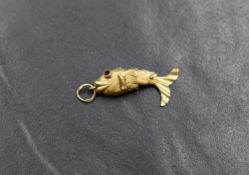 A small yellow metal articulated fish pendant having ruby style eyes, marks worn but possibly 14ct