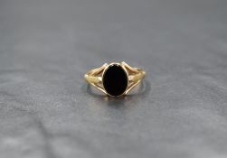 A 9ct gold signet ring having an oval onyx panel in a collared mount to split shoulders, size Q &