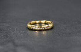 An 18ct gold and diamond band, the twelve diamond chips in a tensions setting, ring size O, 4.9g