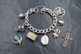 A silver curb link charm bracelet, having seven silver and white metal charms including a locket and