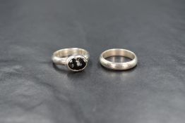 A pair of white metal Artisan made rings made to be worn together, one being a plain band, the other