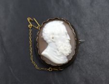 A conch shell cameo brooch depicting a gentleman in profile in a collared white metal mount, no