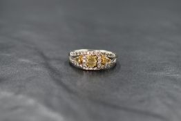 An 18ct white gold diamond ring, the central cushion cut yellow diamond measuring approximately 0.