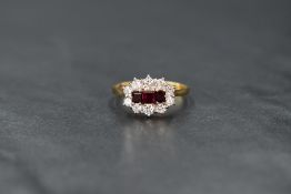 An 18ct gold ruby and diamond cluster ring having three baguette cut central rubies within an oval