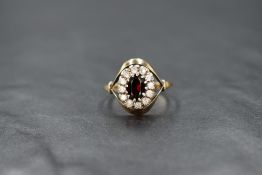 A garnet and clear paste cluster ring having a claw set mount with split shoulders on a 9ct rose