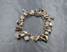 An early 20th century white metal charm bracelet, having thirty-five charms including a