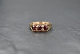 A 9ct gold garnet trilogy ring having a claw set mount in a box style setting with split