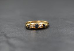 An 18ct gold sapphire and diamond five stone ring, the central round cut sapphire flanked by two