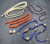 Three strings of beads including branch coral, lapis lazuli and rough cut garnet, a three row string
