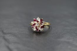 An 18ct gold diamond and ruby swirl cluster ring having a stepped claw set mount on an 18ct gold