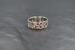 A 1960's 18ct white gold band ring having nine inset small sapphires and a bark effect finish,