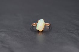 A 9ct rose gold opal ring having an asymmetrical opal cabouchon stone in a 4 claw set mount to