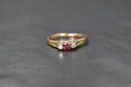 A 9ct gold ruby and diamond trilogy ring, the central round cut ruby flanked by two round