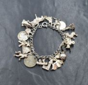 A white metal charm bracelet, having twenty-two charms including a bull, three coins, St. Edward's