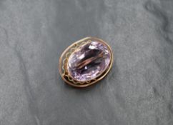 A large yellow metal amethyst brooch, the oval cut amethyst in a bezel setting with pierced