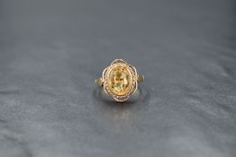 A 9ct gold citrine ring, having an oval stone in a collared setting within a decorative shaped mount
