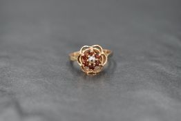 A 9ct gold garnet and seed pearl cluster ring in an open frilled mount, damage to pearl and loop