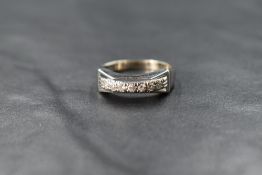 A white metal diamond band, the seven round cut diamonds measuring approximately 0.21 total,