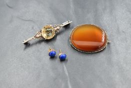 A white metal citrine brooch, the round cut citrine in a four claw setting flanked by thistles,