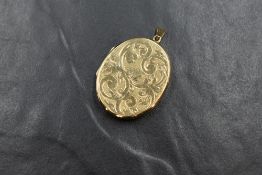 A 9ct gold oval locket having engraved scroll effect decoration, approx 12.4g total & 35mm x 29mm