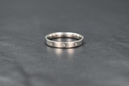 A platinum wedding band having three inset diamond chips, size R & approx 4.7g