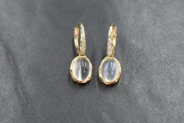A pair of 9ct gold clip loop earrings having collared moonstone cabocho drops from diamond chip
