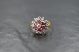 A 9ct gold ruby and diamond cluster ring, the central illusion set diamond chip with a six round cut