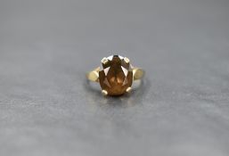 A yellow metal smokey quartz ring having a four claw set raised basket mount to shaped shoulders