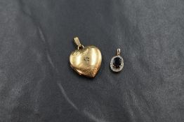 A 9ct gold heart locket, having decorative scroll engraving and set with a central diamond chip,