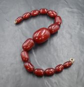 A graduated red bead necklace presumed to be cherry amber, the largest bead measuring