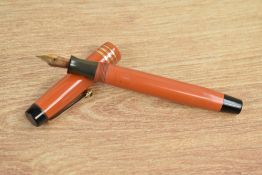 A Parker Duofold Junior button fill fountain pen in orange with three gold bands to the cap having