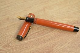 A Parker Duofold Junior button fill fountain pen in orange with two gold bands to the cap having