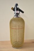A large 20th century glass soda siphon wrapped in a bronze mesh, h35cm