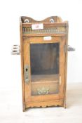 A late 19th / early 20th century smokers cabinet with glass front door, two pipe holders to the side