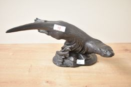 A bronze effect otter study, sculpted sliding into water depicting fish and seaweed, signed to