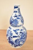 A 19th century Chinese double gourd vase, finally painted with traditional blue dragons on a white