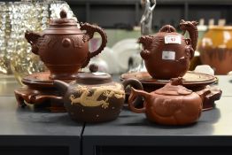 Four Chinese Yixing teapots, each decorated with relief moulded dragon designs, with two circular