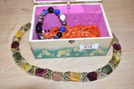 A decorated musical jewellery box, containing a small collection of costume necklaces
