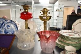An early 20th century brass and ruby red glass oil lamp, h44, sold together with another brass oil