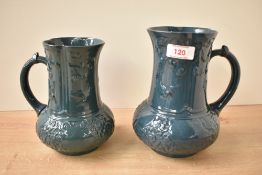 A pair of Victorian aesthetic period green glazed jugs, decorated with exotic birds and foliage,