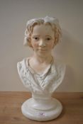 A moulded pottery bust of a young boy, head and shoulders, lightly accented and with painted
