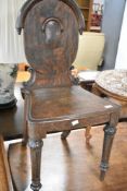 A 19th Century oak hall chair having shield back with turned legs