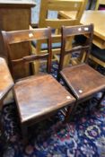 A pair of 19th Century mahogany solid seat dining or hall chairs having rail backs