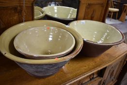 Three assorted antique glazed dairy bowls, various sizes up to 48cm max