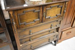 An early 20th Century oak Jacobean revival style tallboy style chest having cushioned panels