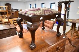 An early 20th Century mahogany footstool having ball and claw feet