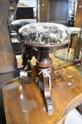 A 19th century mahogany piano stool having circular adjustable seat with moquette style upholstery