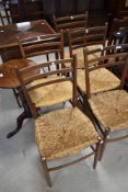 A set of five vintage teak dining chairs having rail backs and rush seats