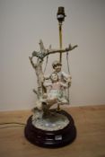 A mid-20th Century Capodimonte porcelain lamp, modelled as two children on a swing and measuring