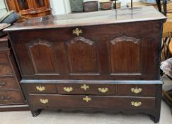 An 18th century oak mule chest with a hinged top and three panel front enclosing a wine rack above